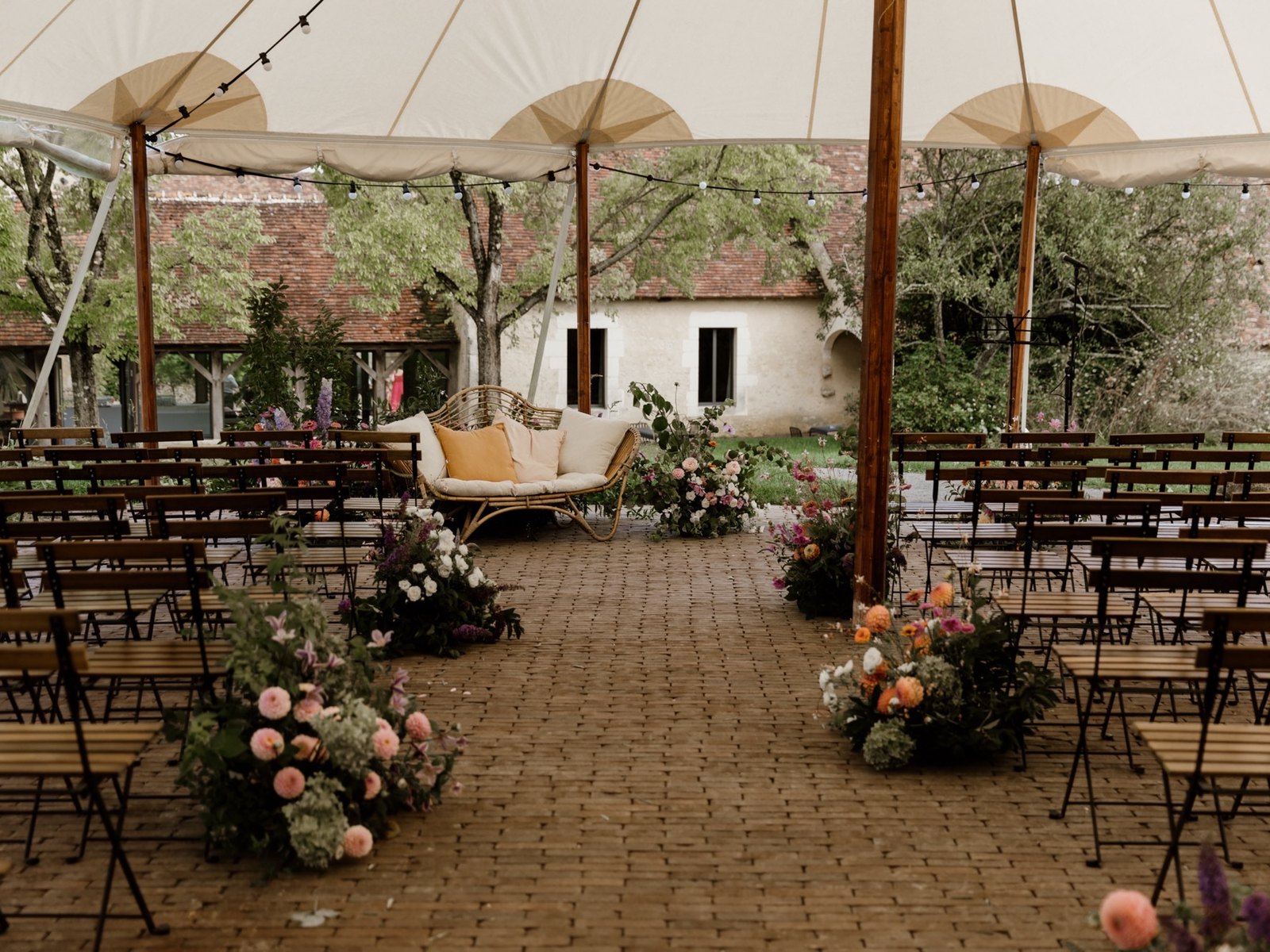 Ceremony set under the marquee, flower-lined aisle