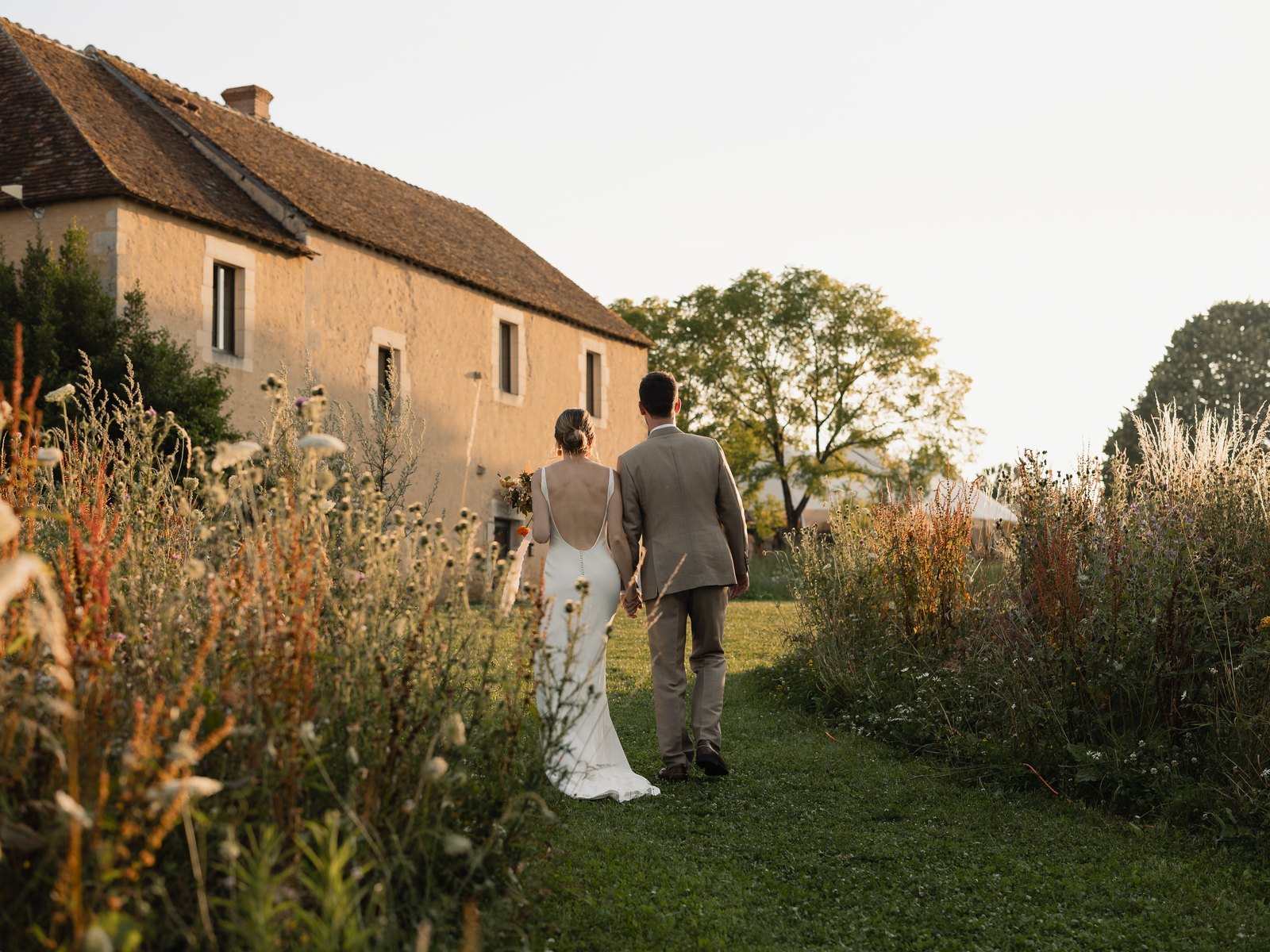 The newlyweds walking back to the house through the wildflower meadow