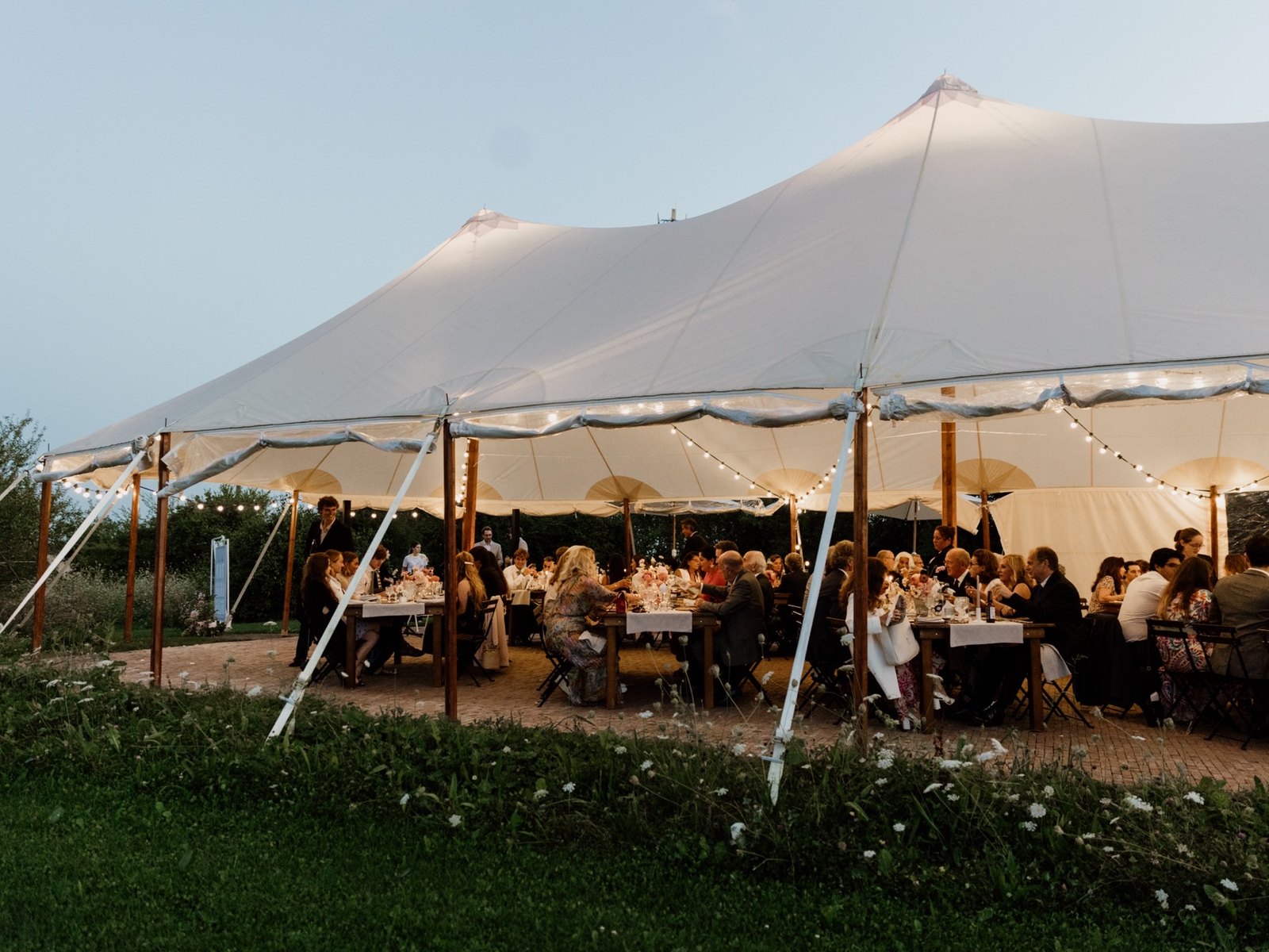 Wedding dinner under the sailcloth marquee at dusk