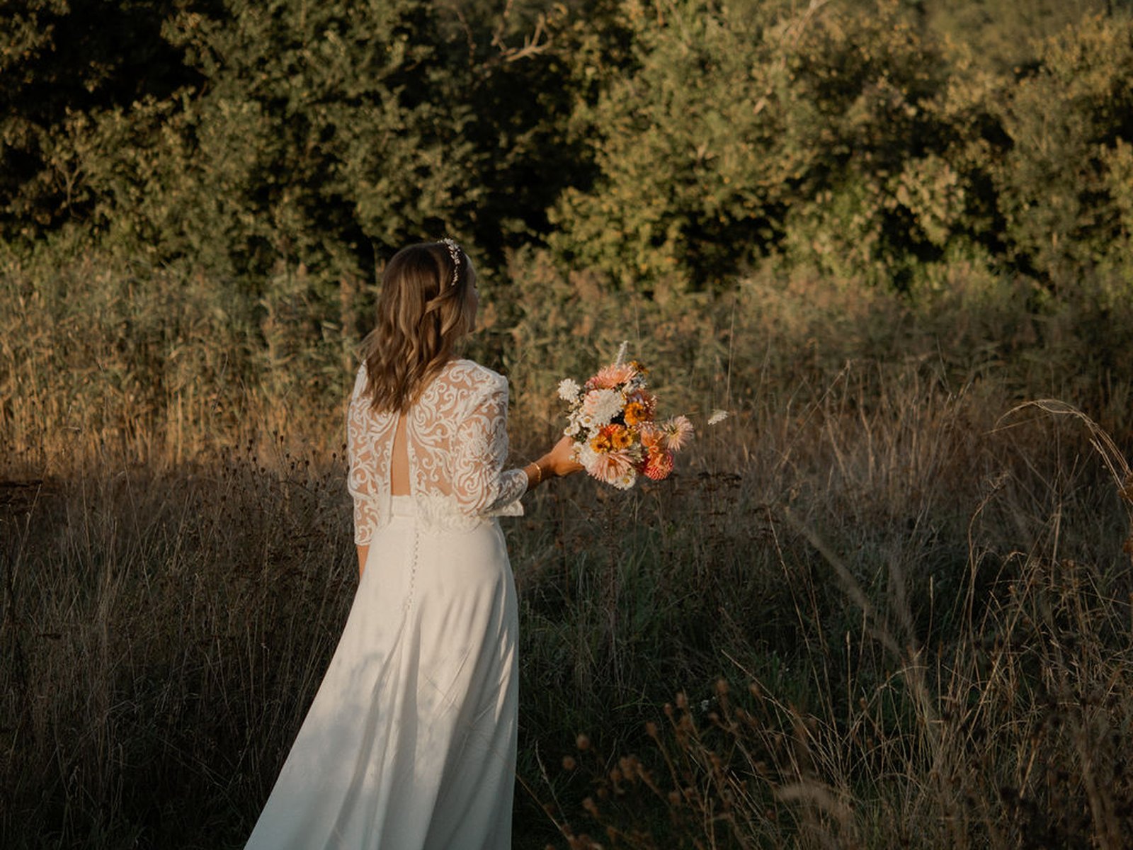 The bride and her bouquet in the meadow at sunset